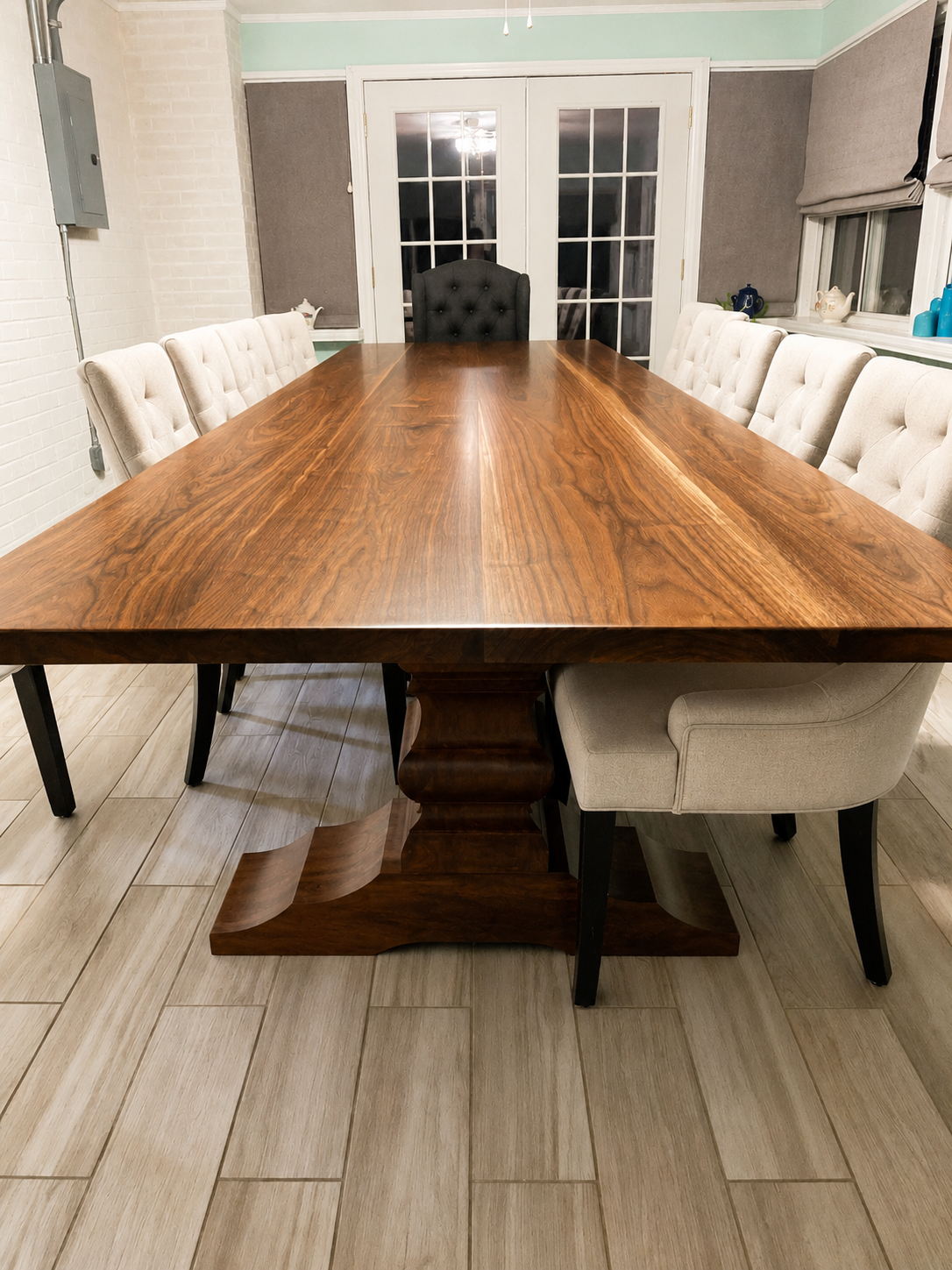 Large walnut dining table with dark wood tabletop and central pedestal base