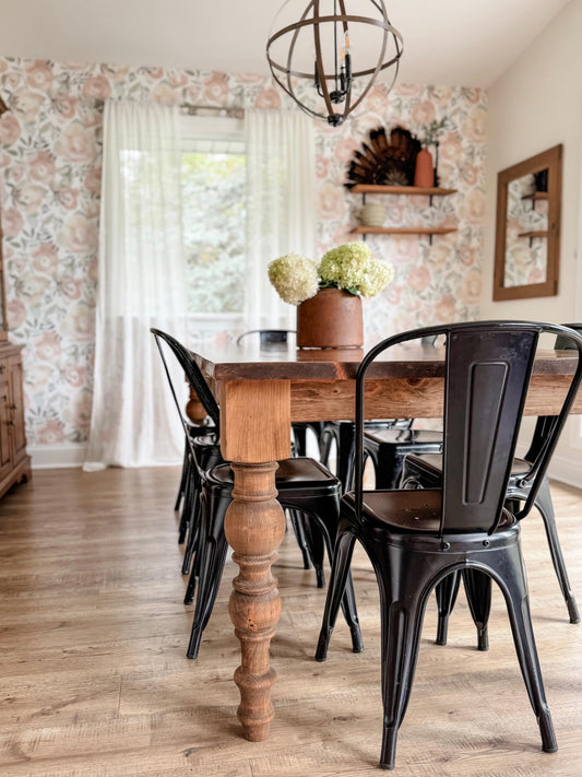 Wood dining table with turned legs and a distressed top, with black dining chairs