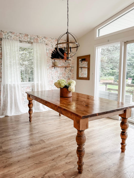 Large wooden dining table with thick legs, warm brown finish and wide tabletop