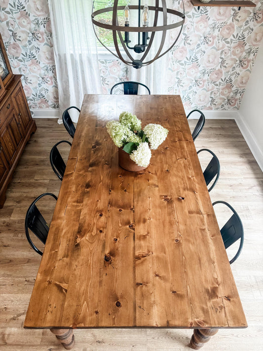 Large farmhouse dining table with natural wood top and turned legs