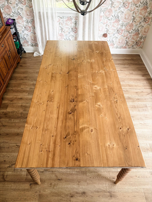 Light wood farmhouse dining table with turned bobbin legs and plank tabletop