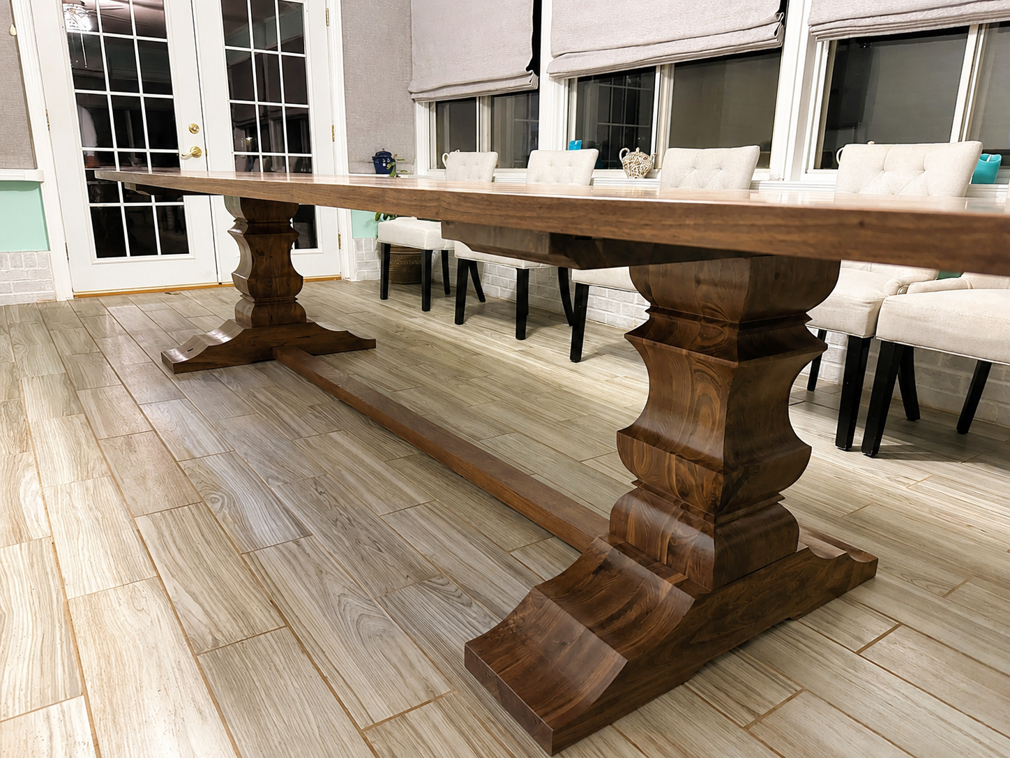 Large walnut dining table with dark wood pedestal base and wide tabletop